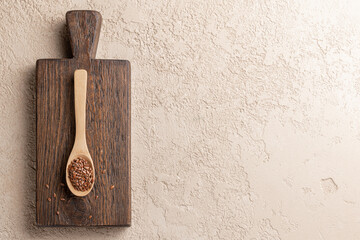 Flax seed in wooden spoon on cutting board. Horizontal. Copy space. Food background. Flat lay.