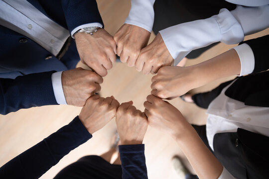 Business team showing expressing strong motivation, engaged in teambuilding activity, making hand circle, keeping fists together. Teamwork, community, corporate friendship concept. Close up, top view