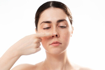 Plastic nose surgery. Face of young caucasian woman touching her crooked nose isolated on white...