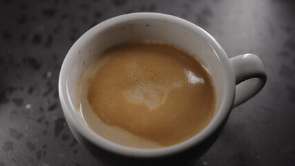 Making cappuccino, pour steamed milk into white cup with espresso
