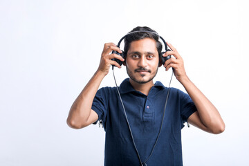 Young indian man listening music and showing expression over white background.