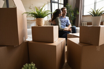 Starting new life together. Young married couple first time realty buyers renters hug on sofa at...