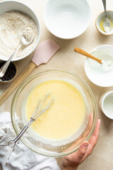 Female hands mixing ingredients for cooking cake in glass bowl, top view. Step by step recipe.
