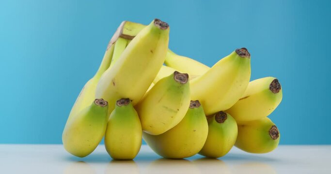 Bananas Yellow Beautiful Ripe Lying on the table on a blue background. Ripe Bananas rotate in a circle. Interesting foreshortening, stock footage.