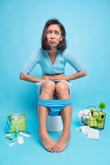 Indoor shot of displeased Asian woman suffers from stomachache indigestion or diarrhea poses poses...