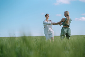 Portrait of two fair-haired girls in fashionable and stylish clothes, against the background of a field. Nature, vacation, relax and lifestyle. Fashion concept.
