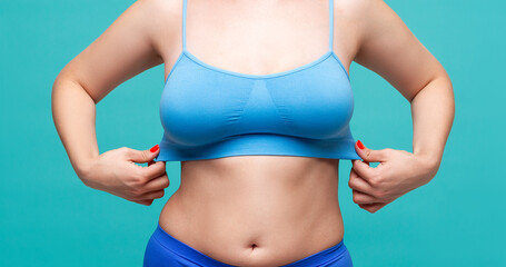 Fototapeta na wymiar Woman in blue top bra with big natural breasts on turquoise background