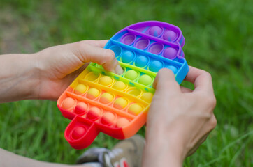 Pop it fidget in the form of ice cream in female hands. Girl in nature plays with pop it