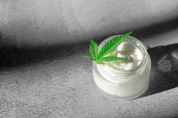 Obraz na płótnie Canvas Hemp-based moisturizer. Jar of cream and hemp leaf. Natural cosmetics made from hemp. Natural body care