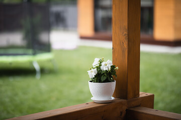 a white pot with a homemade flower stands on the veranda