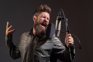 Singing man in a recording studio. Expressive bearded man with microphone. Expressive singer with microphone.
