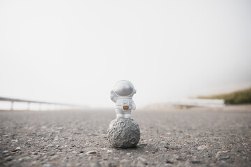astronaut figurine stands on the asphalt road