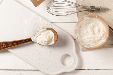 xanthan gum food additive for dough on white plate in wooden spoon with metal whisk