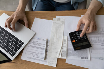 Top above close up view young man doing financial paperwork, calculating domestic utility bills,...