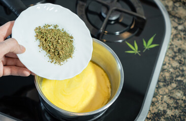 Mixing crushed cannabis with melted butter to prepare marijuana butter or cannabutter, a cannabis edible.