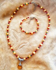 Yellow and Red Pearl Necklace and Bracelet Set on Textured Background