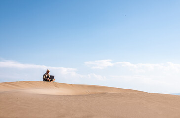 Man using laptop on sand dune