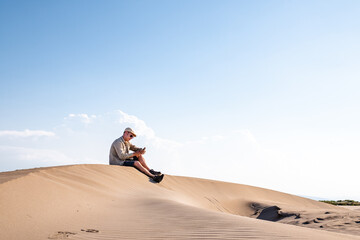 Man using smart phone with internet connection in the desert dunes alone