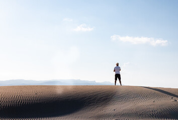 Man calling with a smart phone stand in the desert dunes alone. Copy space