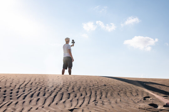 Man filming himself with his cell phone in the desert dunes. Traveling male content creator