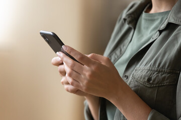 Close up of casual young female hands holding using modern smartphone device indoors. Millennial...
