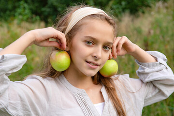 12 year old white girl with a fresh apples  smiles on a green background,  teenager