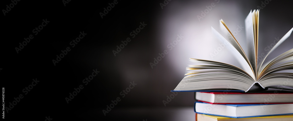 Wall mural hardcover book lying on a stack of other books