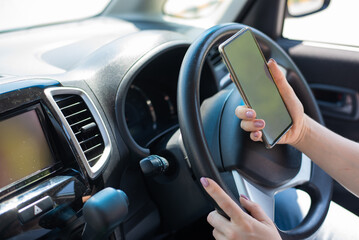 A faceless woman uses a mobile phone while driving a car. The girl uses the navigation in the smartphone