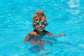 Naklejka premium Curly boy in the pool with glasses