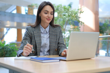 Portrait of a young brunette business woman using laptop at office.