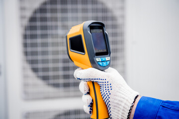 Technician uses a thermal imaging infrared thermometer to check the condensing unit heat exchanger.