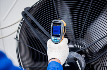 Technician uses a thermal imaging infrared thermometer to check the condensing unit heat exchanger.
