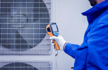 Technician uses a thermal imaging infrared thermometer to check the condensing unit heat exchanger.