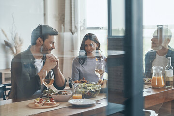 Relaxed multi-generation family communicating and smiling while having dinner together