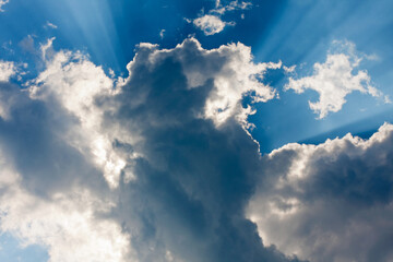 Beautiful blue sky with sunbeams and clouds. Sun rays.