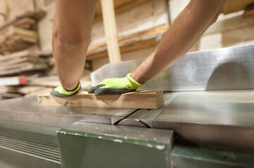 Carpenter processes wood in a furniture workshop. Woodworking and crafts tools