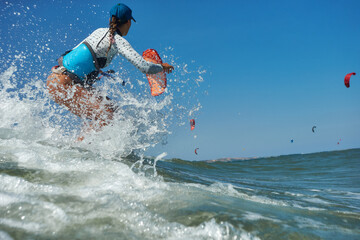 Kite surfer woman jumps with kiteboard  in transition and throws up the board
