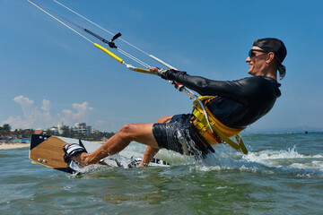 Kite surfer rjumps with kiteboard  in transition and throws up the board