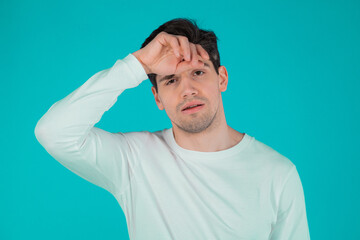 Frustrated european man over teal wall background. Guy is tired, bored of work or studying, he disappointed, helpless