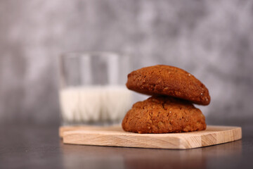 breakfast concept - oatmeal cookies on wooden desk and a glass of milk isolated on gray background