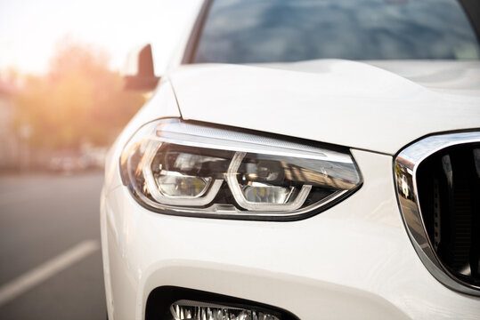 radiator grille and headlight of white beautiful car close up with sun glare on bright sunny day