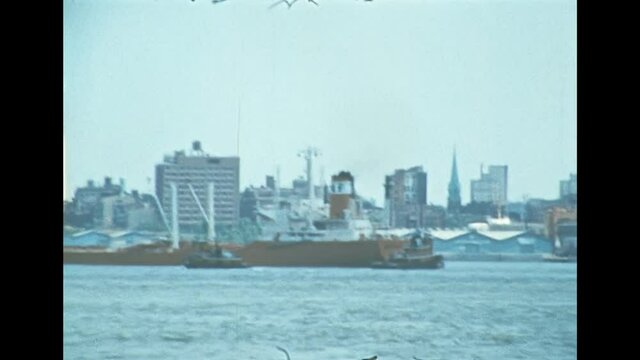 Cargo ship in the skyline the of old New York city. United States America in 1976. Archival of Manhattan downtown skyline from Hudson river by sightseeing cruise.
