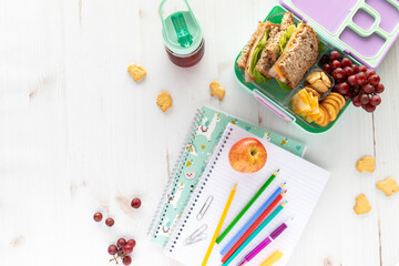Top down view of school supplies and lunch on a light background. Back to school concept.
