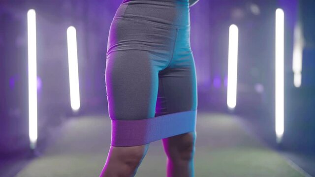 Sexy fitness girl butt while squatting in gym colorful neon lights and haze 4K