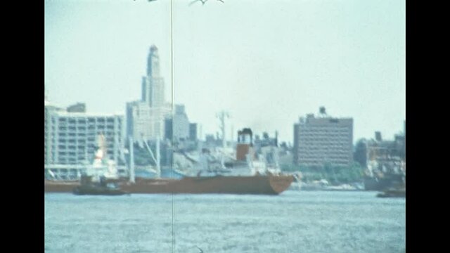 Cargo ship in the Manhattan pier by the old skyline of New York city. United States America in 1976. Archival of Manhattan downtown skyline from Hudson river by sightseeing cruise.
