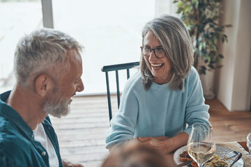 Happy senior couple communicating and smiling while having dinner together
