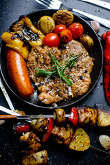 Steak on the plate and black background sprinkled with salt and pepper.

