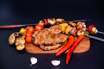 Steak on a wooden cutting board and black background sprinkled with salt and pepper.