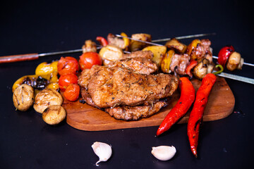 Steak on a wooden cutting board and black background sprinkled with salt and pepper.