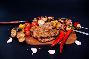 Steak on a wooden cutting board and black background sprinkled with salt and pepper.